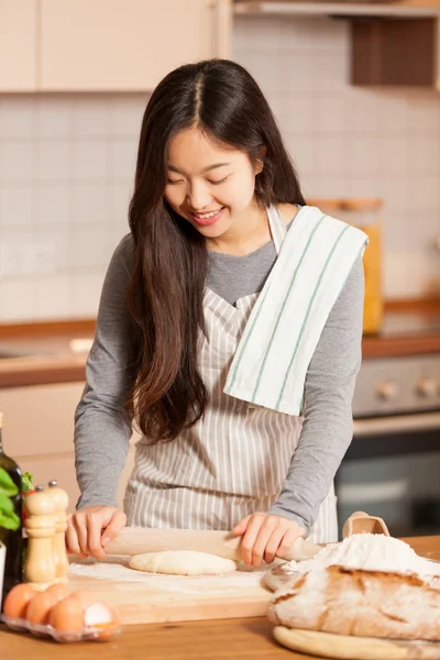 Asian woman is baking bread in her home kitchen