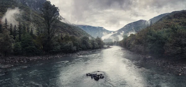 Mountain river with fog and rain. dark and mystical landscape