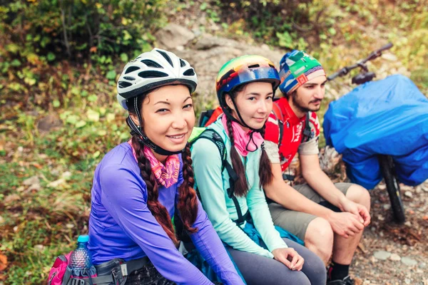 Hiking in mountains. Three bikers sitting on mountain serpentine dirt road.