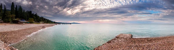 Panorama of pebble beach on the coast and the azure waters of the sea. Abkhazia, Pitsunda.