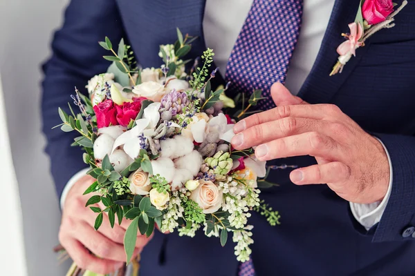 The groom holding cotton wedding bouquet of flowers