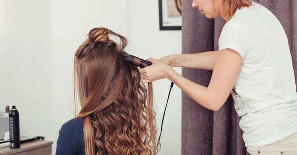 Master of style makes beautiful woman brown hair waved.