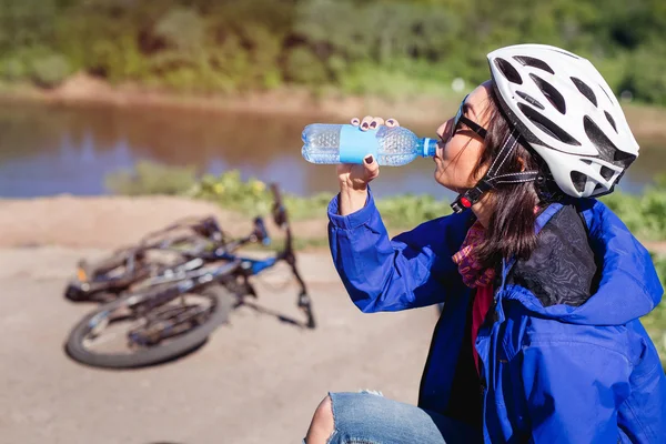 Young girl drinks water from a bottle after mountain biking