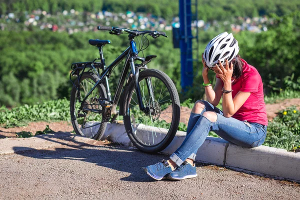 Woman wuth bicycle in trouble holds hands over head