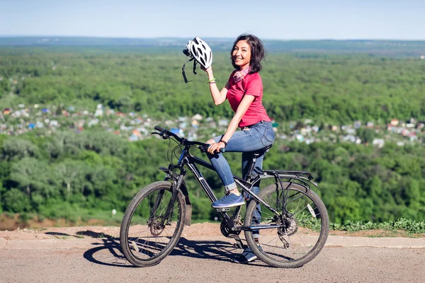 Bike helmet - woman putting biking helmet on during bicycle ride