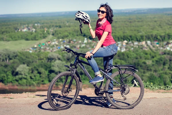 Bike helmet - woman putting biking helmet on during bicycle ride