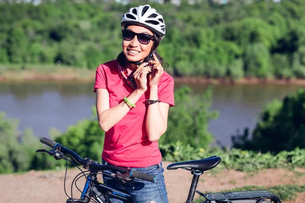 Bike helmet - woman putting biking helmet on during bicycle ride