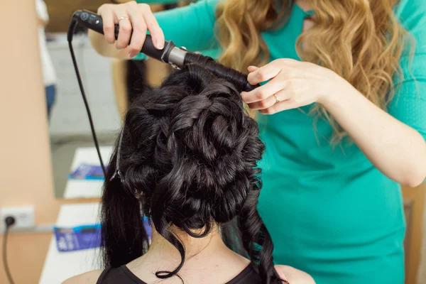 Evening hairstyle. brunette doing hairdresser and styling in bar