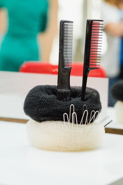 Trendy stand for combs and round hair brushes, on barber salon background