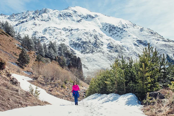 Young woman hiker hiking on mountain trail at early spring in Caucasus mountains
