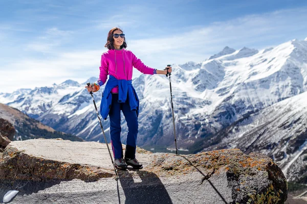 Hiker woman walking on mountain trail with hiking sticks, looking at view in Elbrus region, Caucasus mountains
