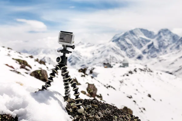 Action camera mounted on a tripod gorilla with snow-capped mountains in the background