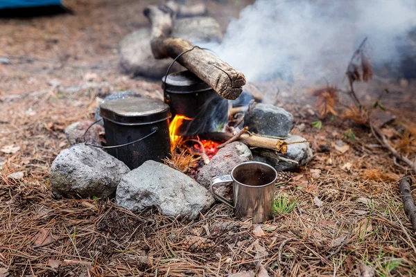 Kettle on fire in the forest during hike or trekking in nature. The concept of camp food