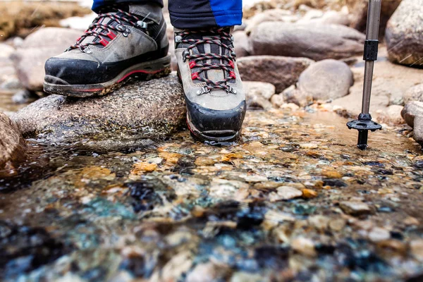 Young woman traveling in mountains, wading rocky river