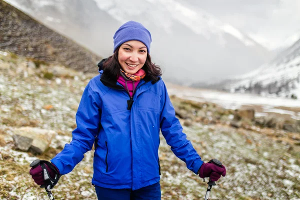 Young Woman hiking in the Mountains. Its snowing and sunny, early spring