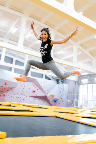 Happy young woman jumps on a trampoline.