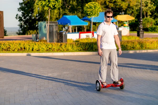A man rides a hoverboard giroskutere or on a sunny day in the pa