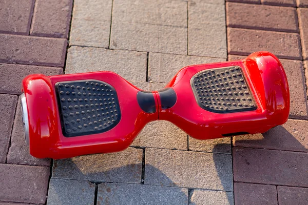Red Electric mini hover board scooter on road in park