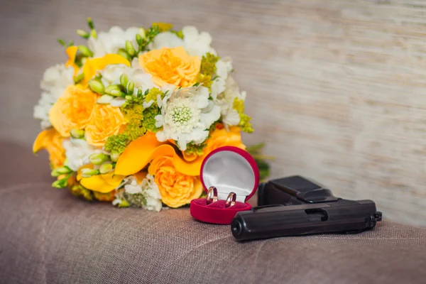 Gun, wedding rings and bouquet