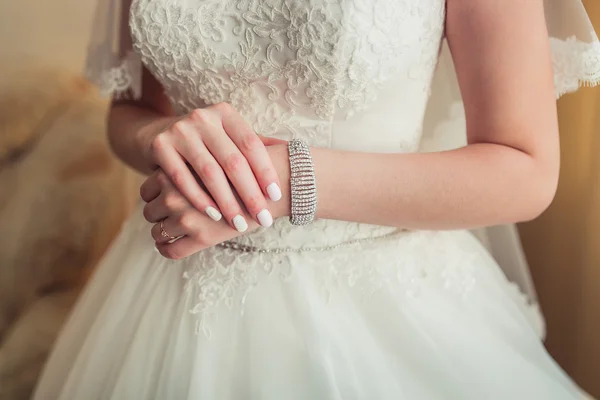 The gentle hands with bracelet of the bride in lace white dress