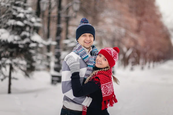 A couple in love cute sweaters for walks in the snowy winter Park. The concept of Valentine\'s day