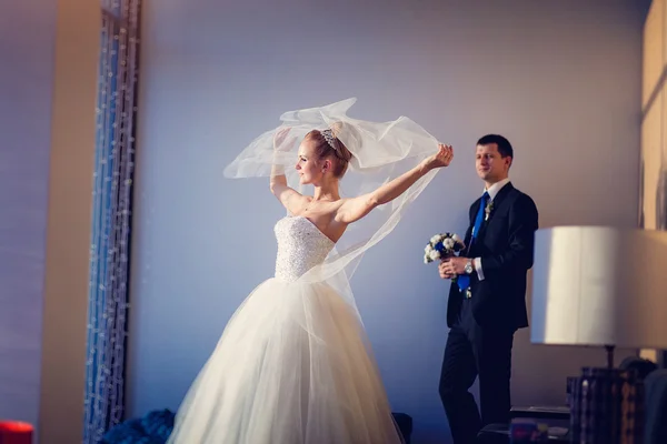 The bride with veil and groom in interior of hotel