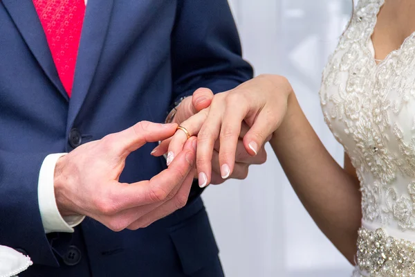 Groom wears bride a gold ring on her finger.