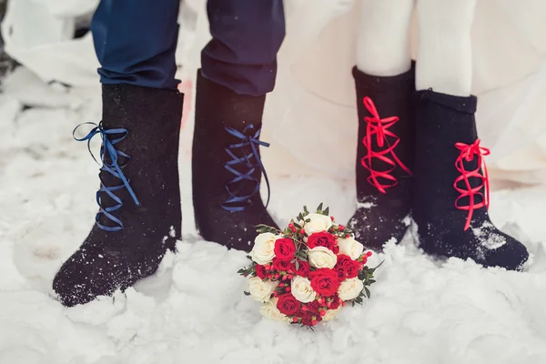 A closeup of the feet of the bride and groom in felt boots on sn