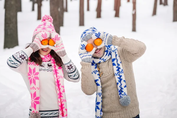 Loving couple in the winter park. Couple playing with fruits and