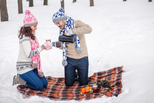 Couple pours tea in mug from thermos at winter Park.