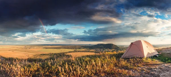 Camping tent in the countryside. Summer, blue sky, clouds and green hills