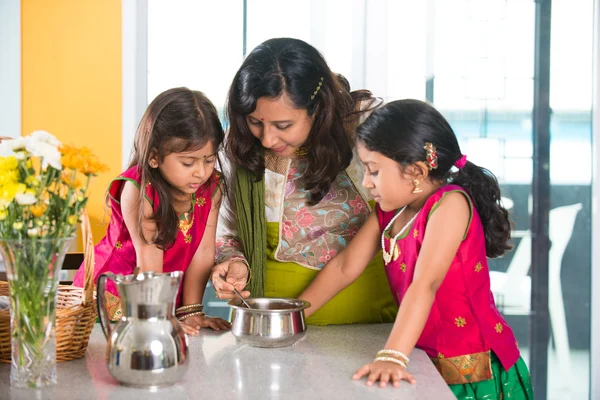 Indian mother cooking with daughters
