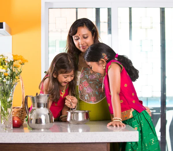 Indian mother cooking with daughters