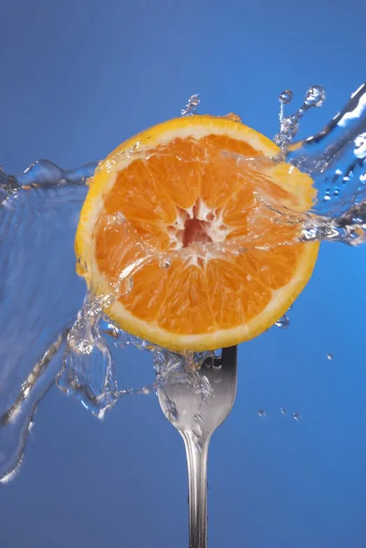 Orange fruit fork water splash blue concept health