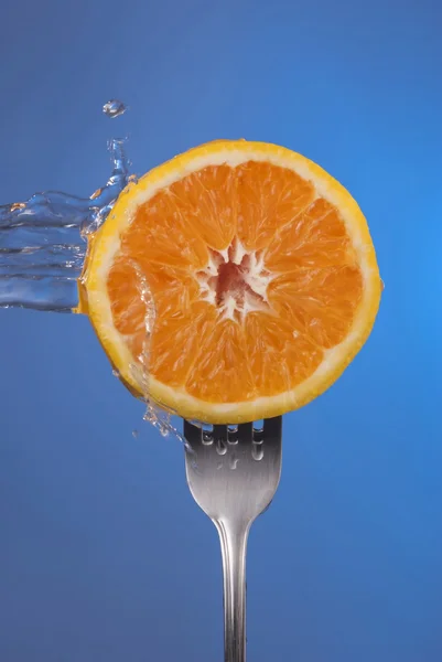 Orange fruit fork water splash blue concept health