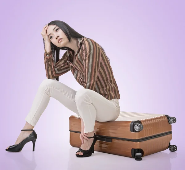 Asian woman thinking and sitting on a luggage