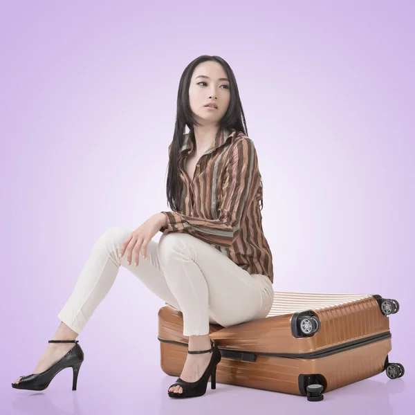 Asian woman thinking and sitting on a luggage