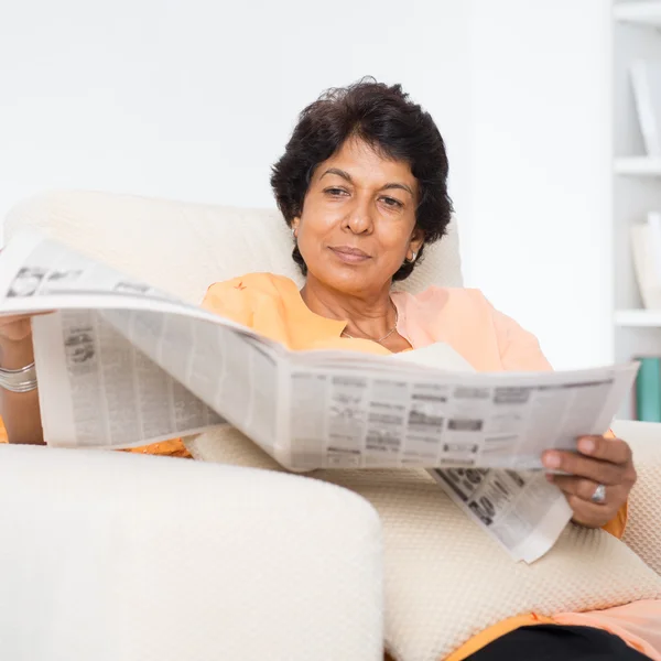 Indian mature woman reading news paper