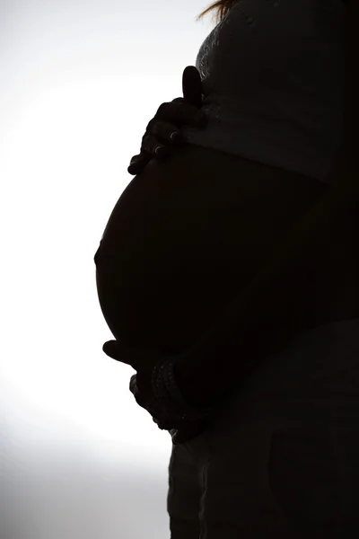 Unrecognizible pregnant woman with hands on belly black and whit