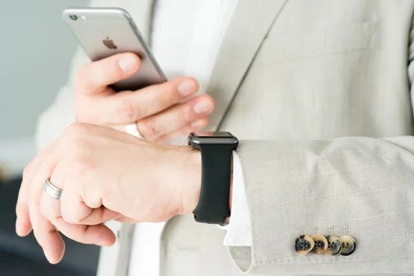 Businessman using the Apple Watch and an Apple iPhone 6