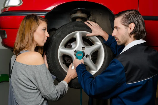 Auto mechanic and female trainee changing a car tyre in garage