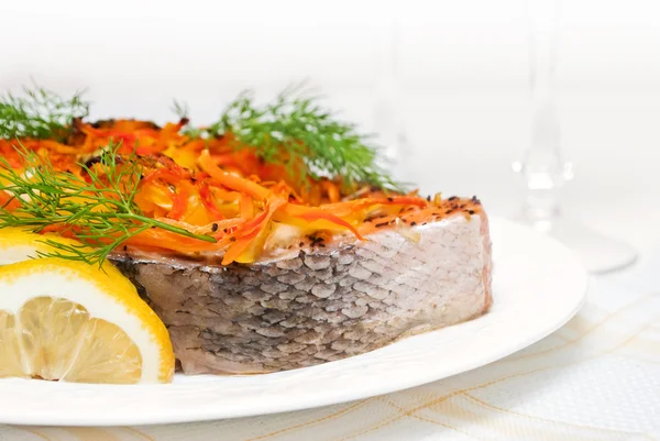 Cooked salmon covered with carrots and dill with lemon pieces on