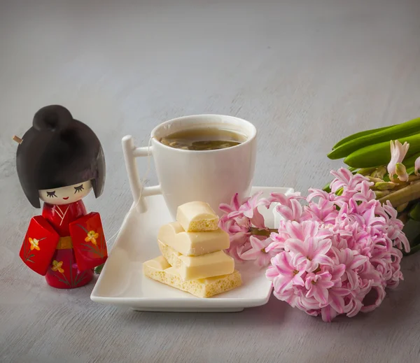 Cup of tea, chocolate, toy and flowers