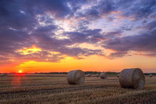 Sunset over rural road and hay bales