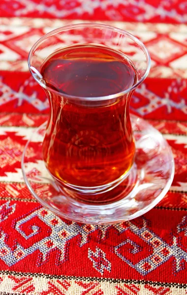 Turkish tea in traditional glass cup on handmade arabic ornamental tablecloth, travel in Turkey