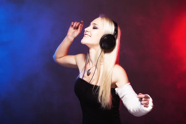 Girl dancing with broken arm and headphones