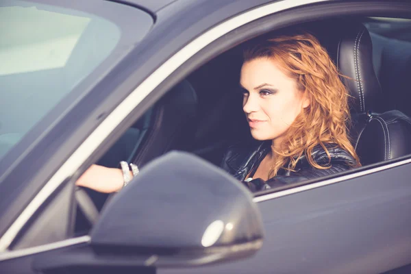 Female driver, driving a new black car. Hands on the steering wheel.