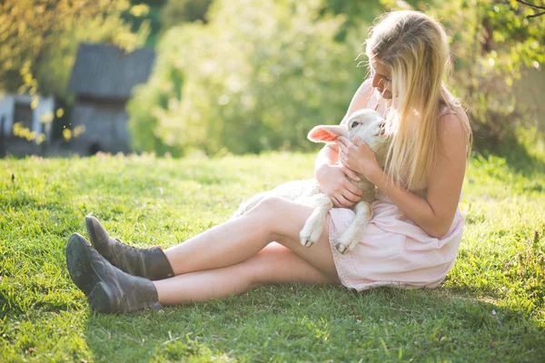 Close up image of cute, young lamb taking care by farmer woman. Happy woman smiling and holding a cute lamb.