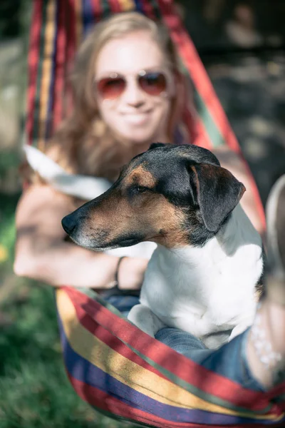 Portrait of a woman with her beautiful dog lying in a hammock outdoors