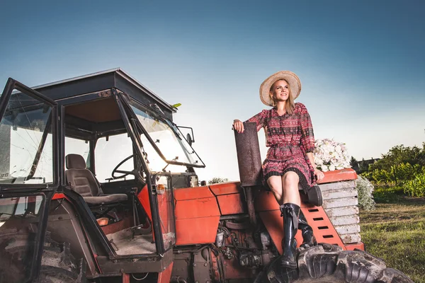 Farmer woman lying on old red tractor